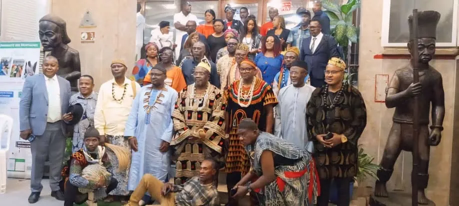 Photo de famille de la conférence-formation 2024, entre deux grandes sculptures traditionnelles