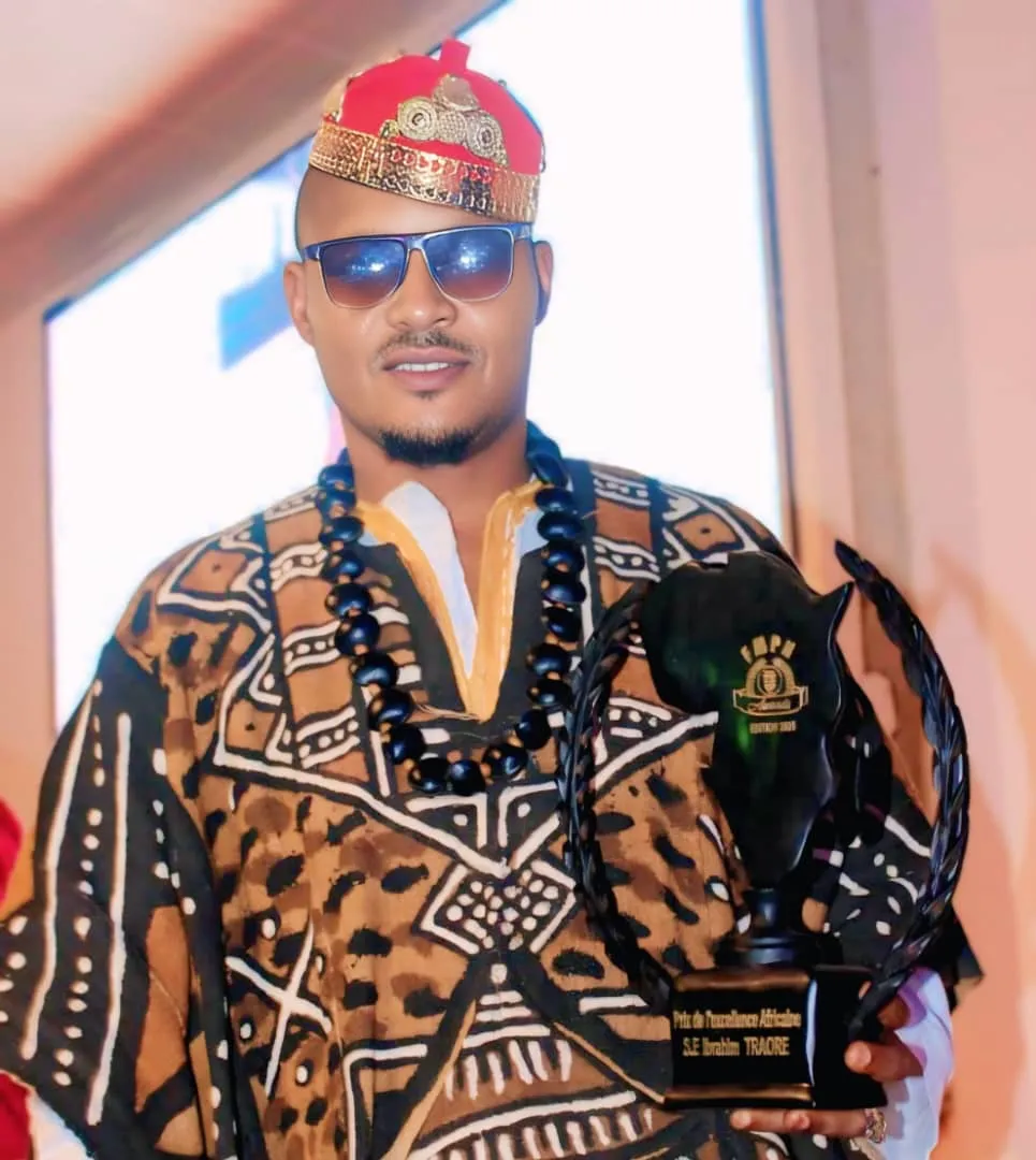 Joseph Kuika, coiffe rouge et or, tenant le trophée du Prix de l’excellence africaine des FMPN Awards 2025
