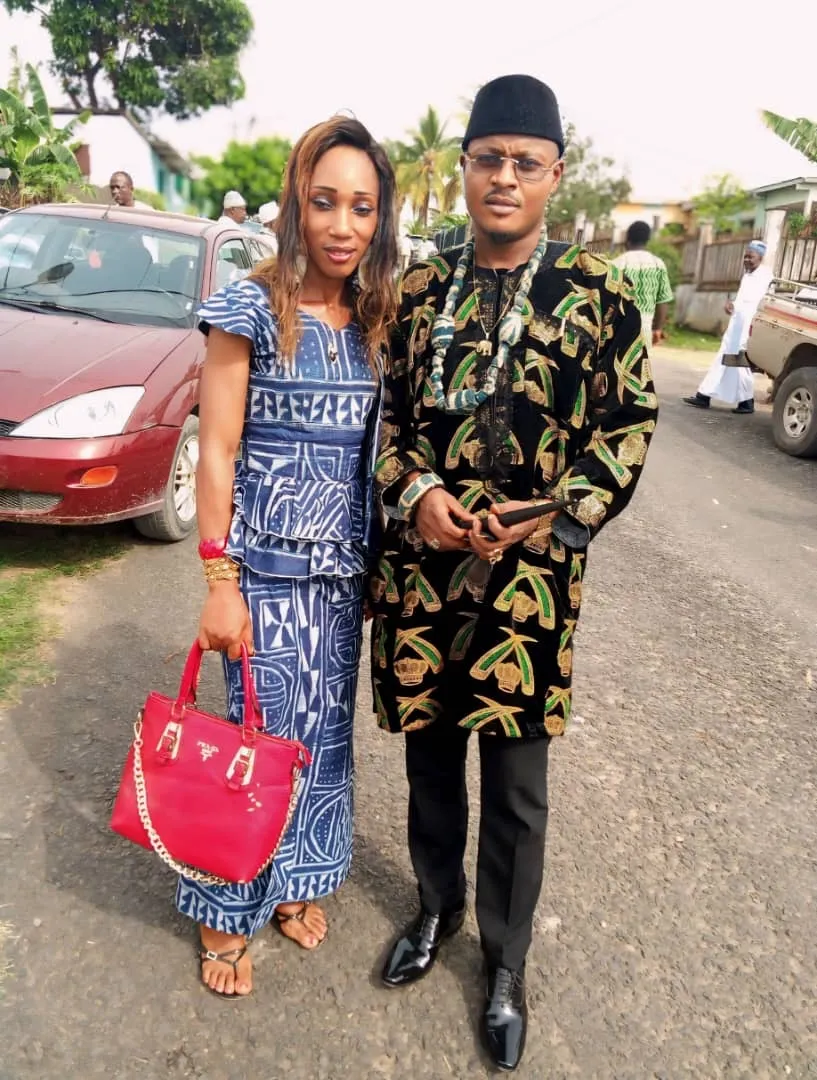 Joseph Kuika en tunique de velours noir brodée or et collier de perles, aux côtés d’une invitée en robe indigo