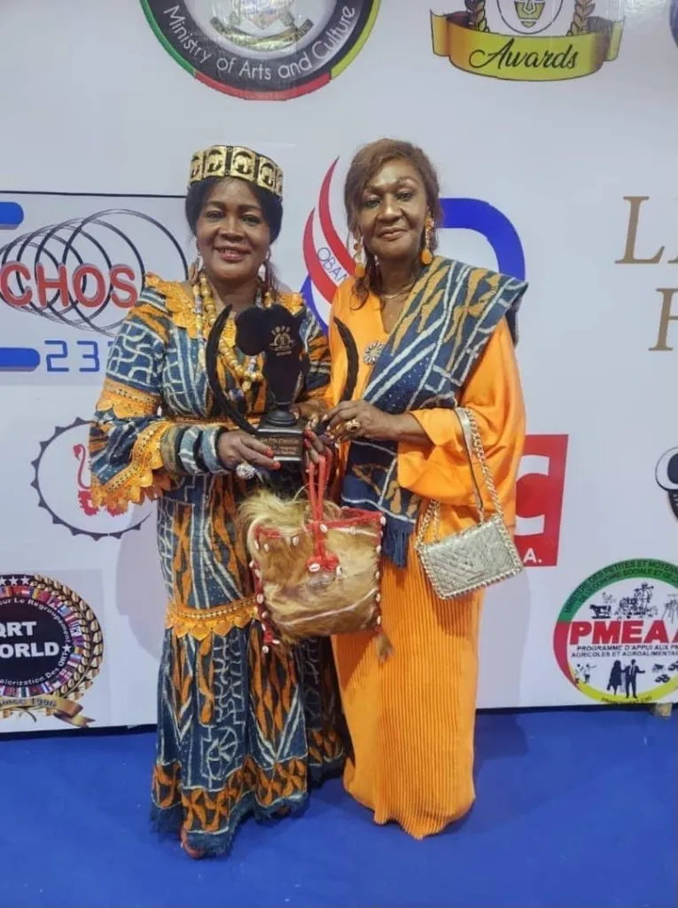 Deux femmes en tenue traditionnelle tenant un trophée en forme d’Afrique